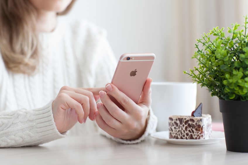 Woman holding in the hand iPhone 6 S Rose Gold in cafe. iPhone 6S was created and developed by the Apple inc.