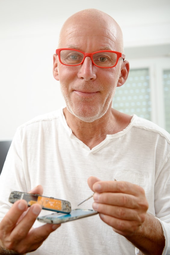 a mature man repaired a smartphone in his home