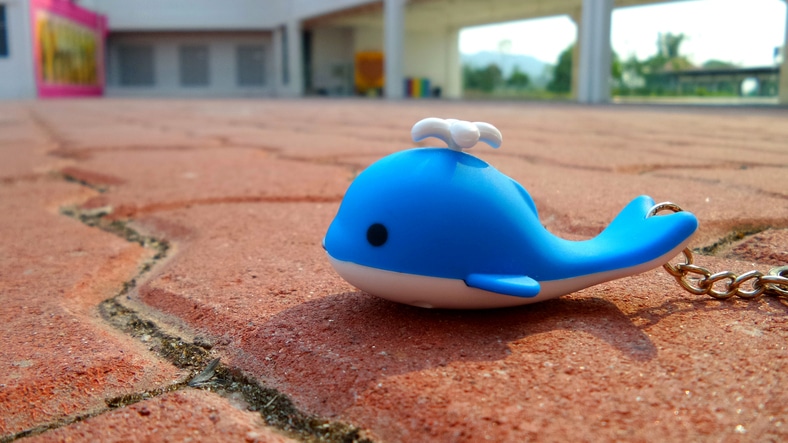 cute blue whale key chain on a red brick ground.